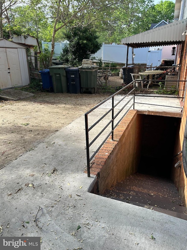 exterior space featuring a storage unit, fence, and an outbuilding