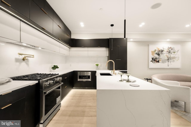 kitchen with light stone counters, modern cabinets, gas range, dark cabinetry, and a sink