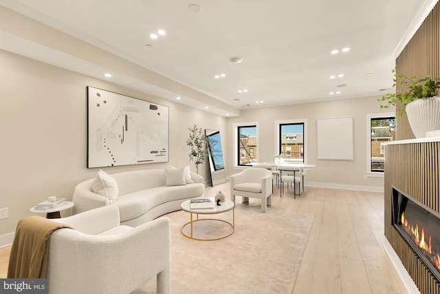 living room with light wood-style floors, plenty of natural light, a glass covered fireplace, and recessed lighting