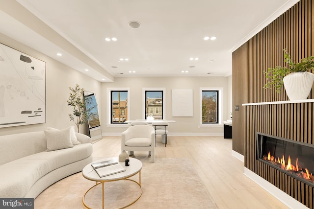 living area featuring light wood-style floors, baseboards, a glass covered fireplace, and recessed lighting