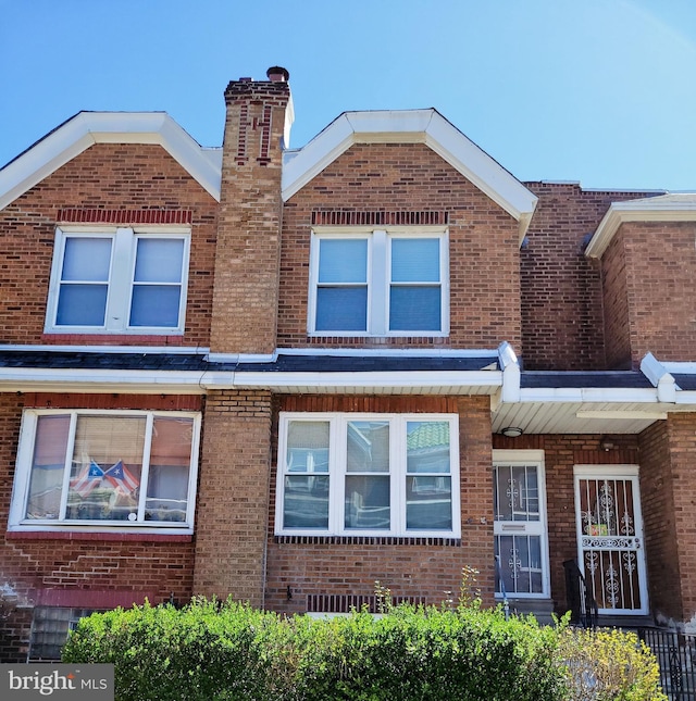 view of front of home with brick siding and a chimney