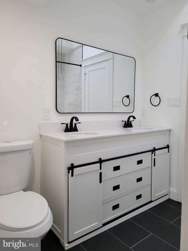 bathroom with toilet, tile patterned floors, double vanity, and a sink
