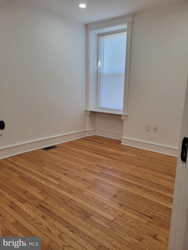 empty room featuring visible vents, baseboards, and hardwood / wood-style flooring