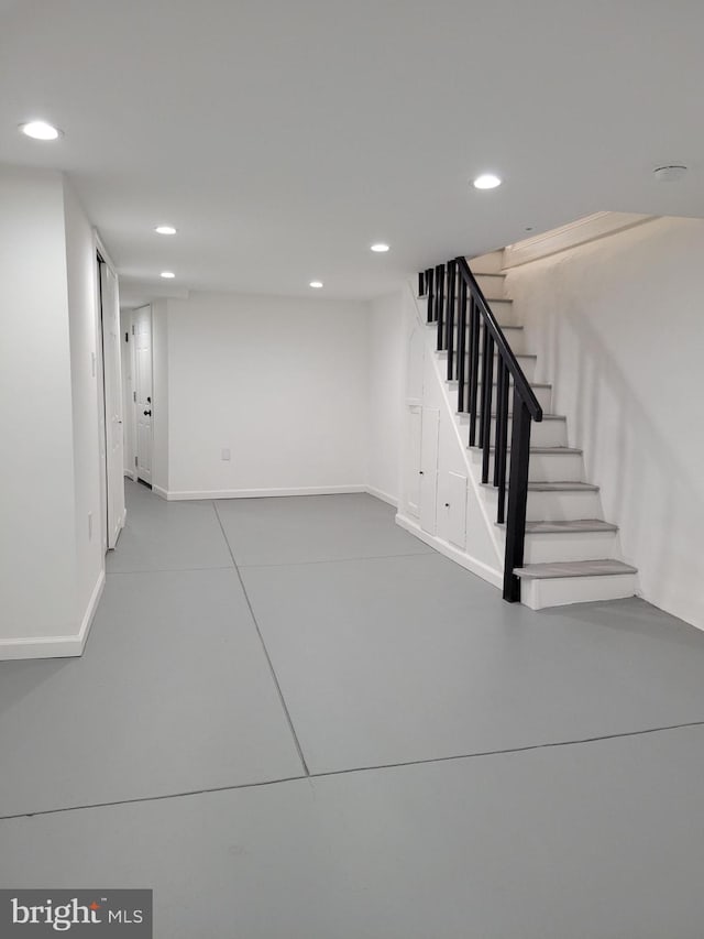 finished below grade area featuring tile patterned floors, baseboards, recessed lighting, and stairs