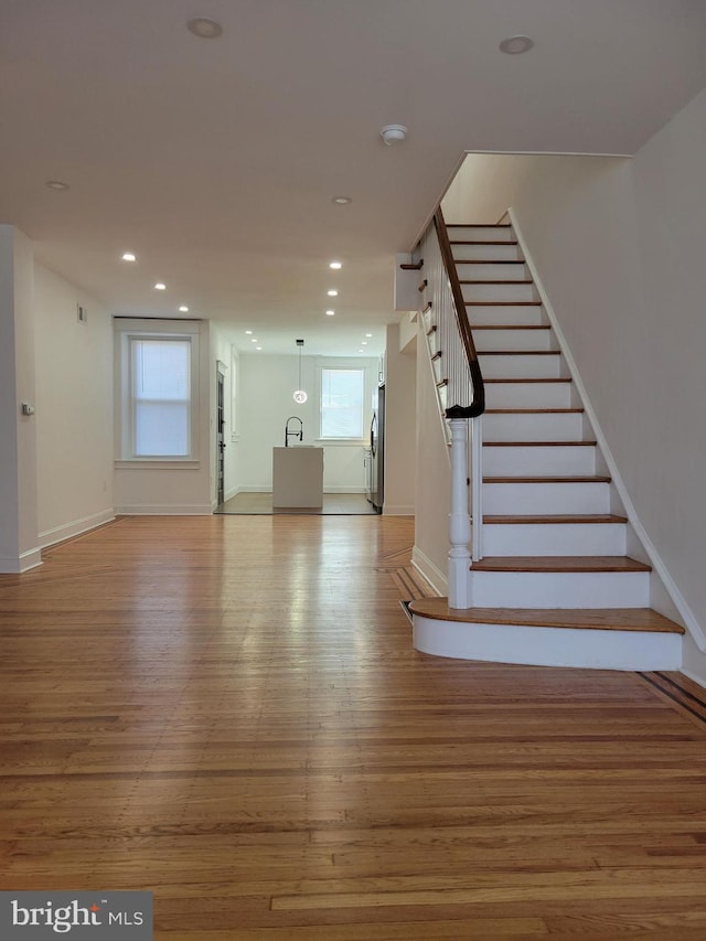 staircase featuring a wealth of natural light, recessed lighting, wood finished floors, and baseboards