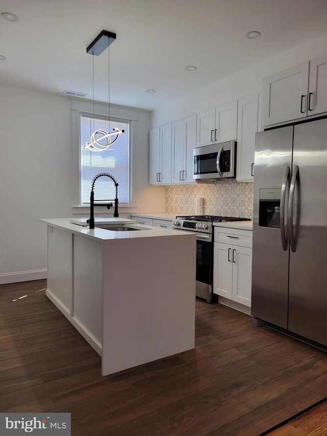kitchen featuring appliances with stainless steel finishes, an island with sink, visible vents, decorative backsplash, and a sink