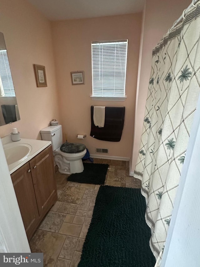 bathroom with toilet, vanity, and a shower with shower curtain