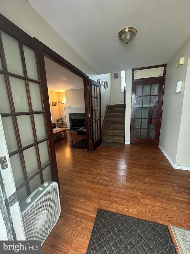 hallway featuring wood finished floors, stairs, and baseboards