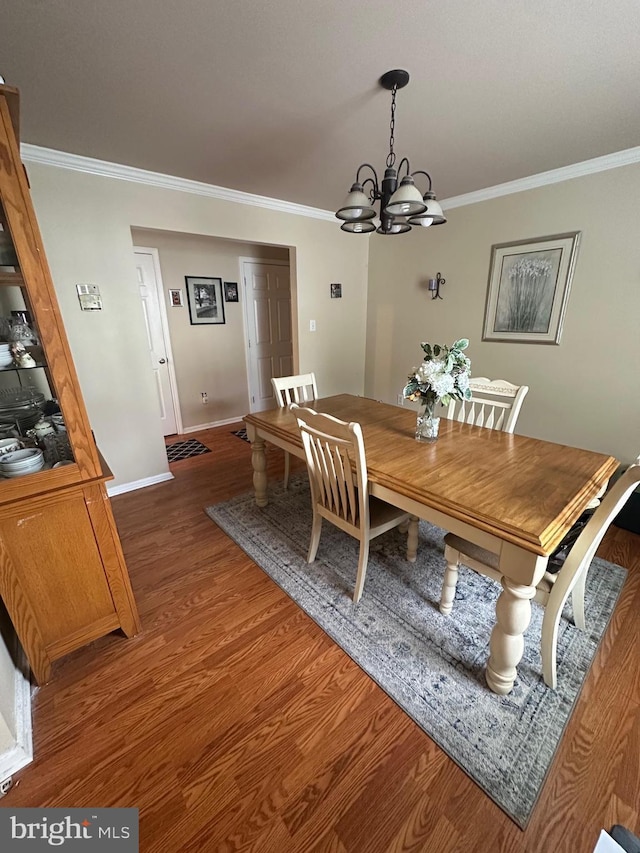dining area featuring a chandelier, ornamental molding, wood finished floors, and baseboards