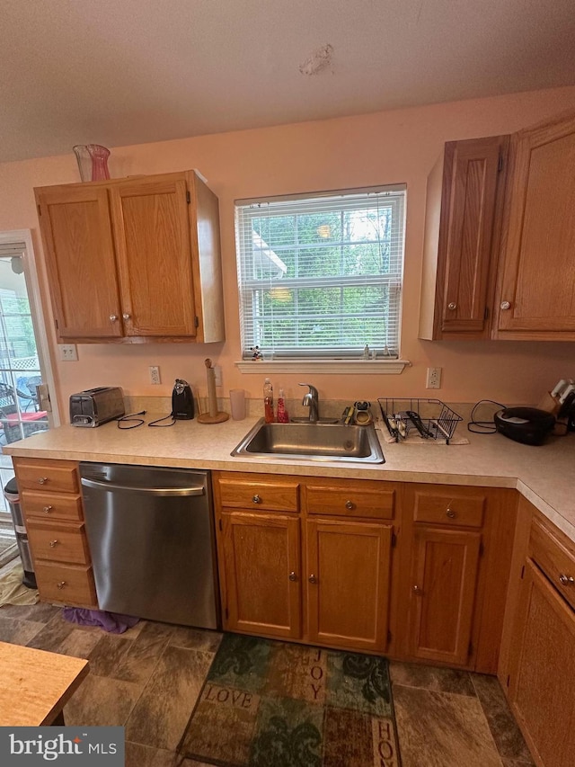 kitchen featuring dishwasher, a sink, light countertops, and healthy amount of natural light