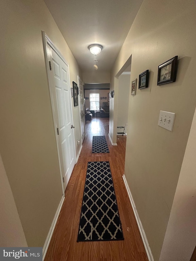 hallway featuring wood finished floors and baseboards