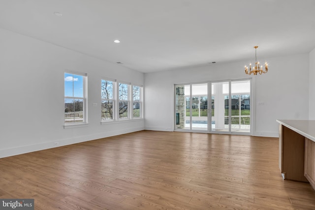 85 Quiet Creek Dr, Gettysburg, PA 17325 - unfurnished living room with light wood finished floors, a healthy amount of sunlight, an inviting chandelier, and baseboards