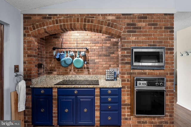 2200 Harpoon Dr, Stafford, VA 22554 - kitchen with stainless steel microwave, wall oven, blue cabinets, black electric stovetop, and lofted ceiling