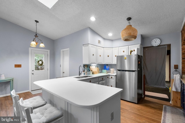 2200 Harpoon Dr, Stafford, VA 22554 - kitchen featuring freestanding refrigerator, a sink, a peninsula, white cabinetry, and light wood-style flooring