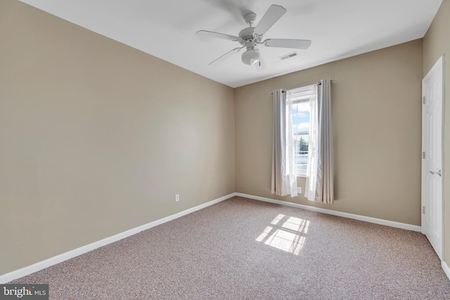 carpeted spare room featuring visible vents, a ceiling fan, and baseboards