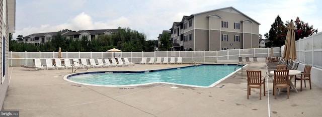 community pool with a patio and fence