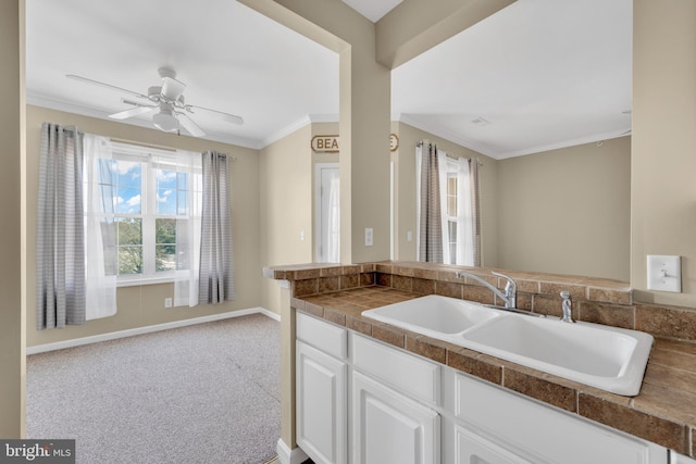kitchen with white cabinetry, tile counters, ornamental molding, and a sink