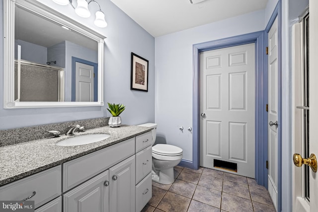 bathroom featuring tile patterned flooring, vanity, an enclosed shower, and toilet