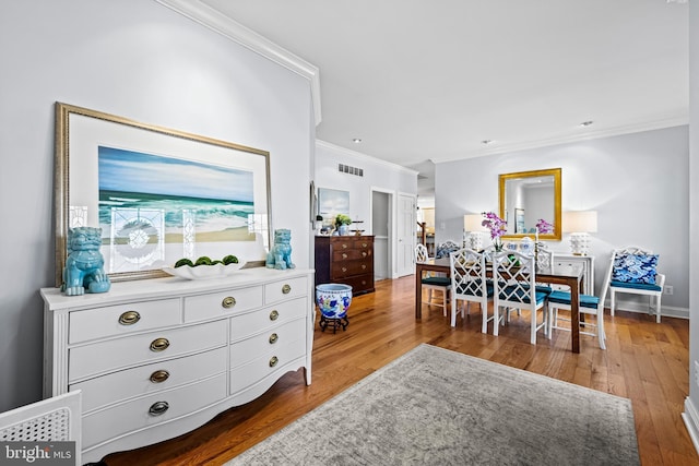 interior space featuring visible vents, ornamental molding, baseboards, and hardwood / wood-style flooring