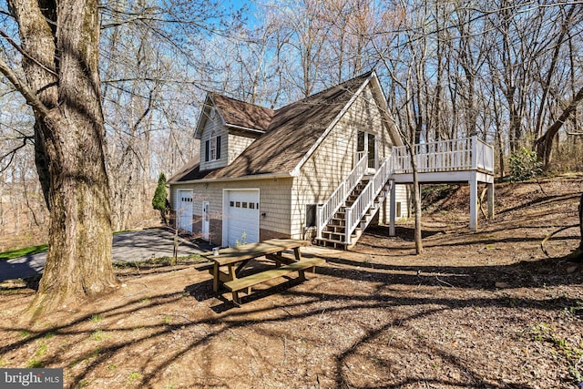 view of side of property featuring stairway, a deck, and driveway