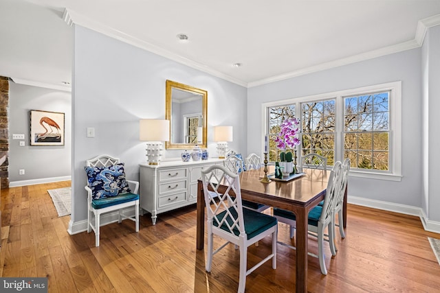 dining space featuring light wood-style flooring, baseboards, and ornamental molding