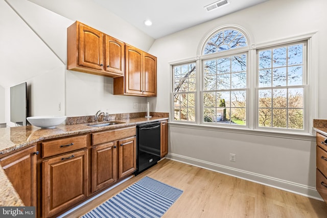 kitchen with visible vents, dishwasher, a sink, brown cabinets, and light wood finished floors