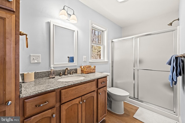 bathroom with a shower stall, vanity, toilet, and wood finished floors