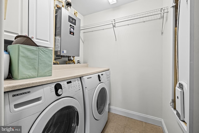 laundry area with light tile patterned floors, baseboards, water heater, washer and clothes dryer, and cabinet space