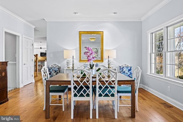 dining room featuring hardwood / wood-style floors, visible vents, baseboards, and crown molding