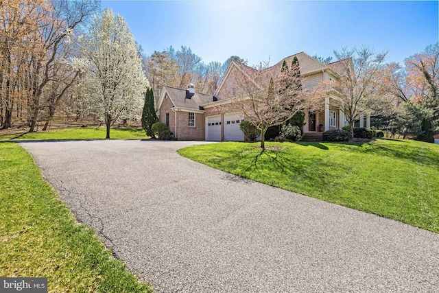 view of front of house featuring brick siding, an attached garage, driveway, and a front lawn