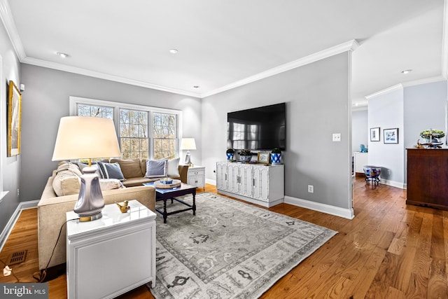 living room with visible vents, baseboards, ornamental molding, and wood finished floors