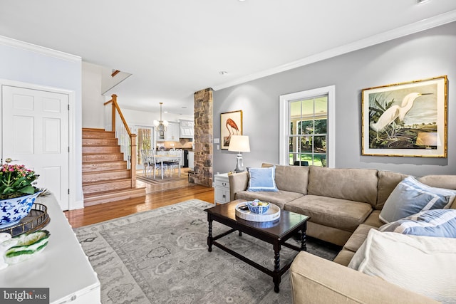 living area with crown molding, stairway, and wood finished floors