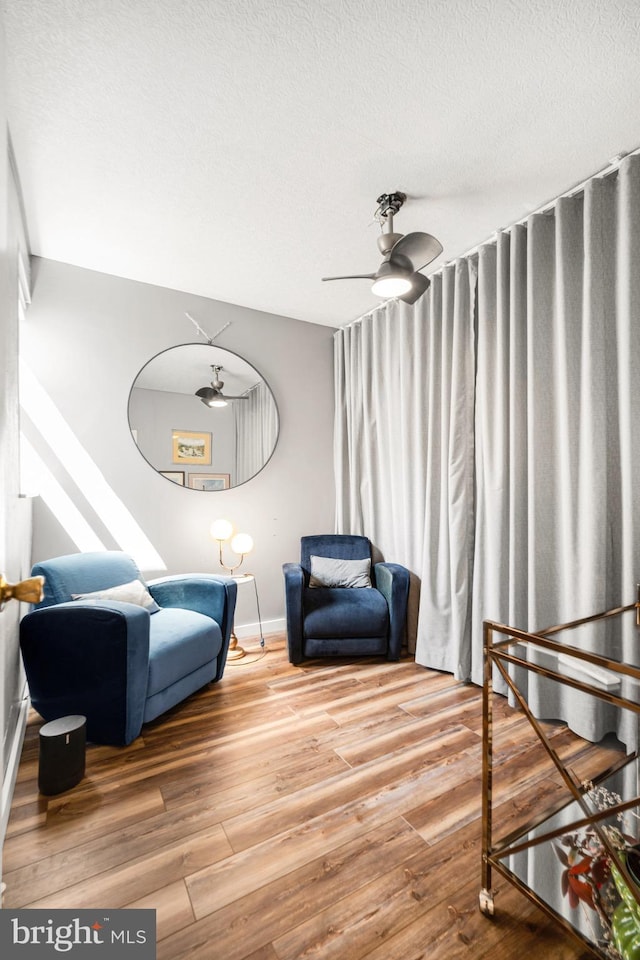 living area with a textured ceiling, wood finished floors, and baseboards