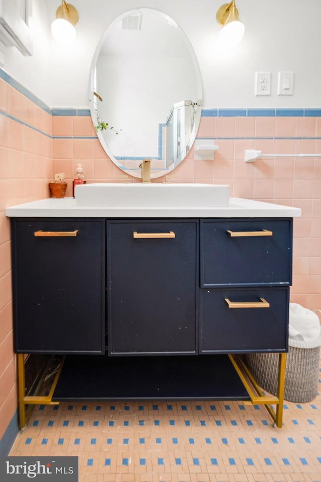 bathroom featuring vanity, tile walls, visible vents, and a wainscoted wall
