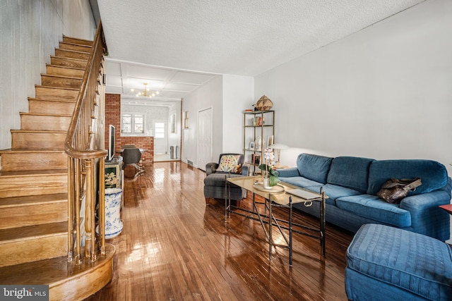 living room with wood-type flooring, stairway, an inviting chandelier, and a textured ceiling