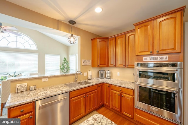 869 Bourban Ln, West Grove, PA 19390 - kitchen featuring stainless steel appliances, lofted ceiling, a peninsula, light stone countertops, and light wood finished floors