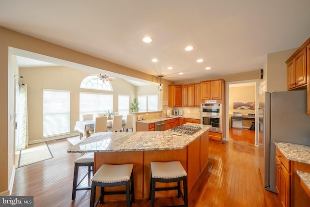 869 Bourban Ln, West Grove, PA 19390 - kitchen with appliances with stainless steel finishes, light stone counters, a breakfast bar area, light wood finished floors, and recessed lighting