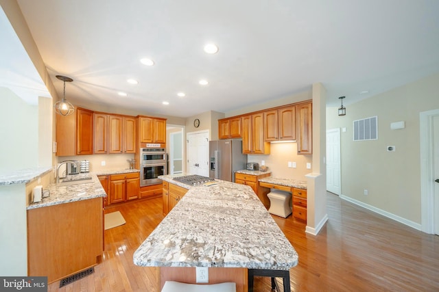869 Bourban Ln, West Grove, PA 19390 - kitchen with appliances with stainless steel finishes, recessed lighting, a center island, light wood-type flooring, and light stone counters