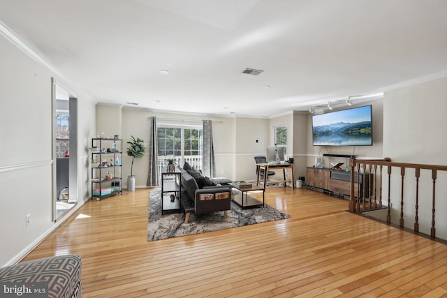 living room featuring visible vents, light wood finished floors, and ornamental molding