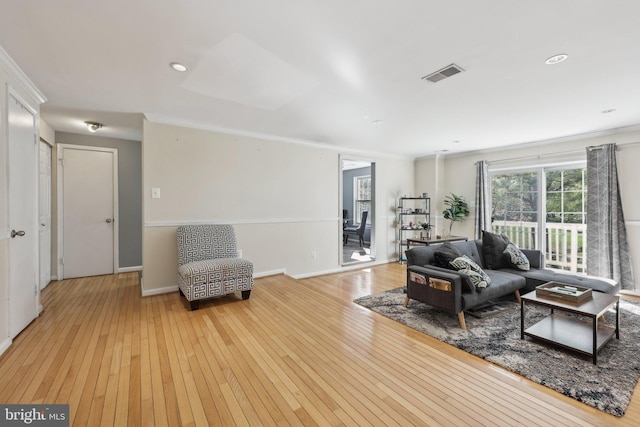 living room featuring baseboards, visible vents, light wood-style floors, and crown molding