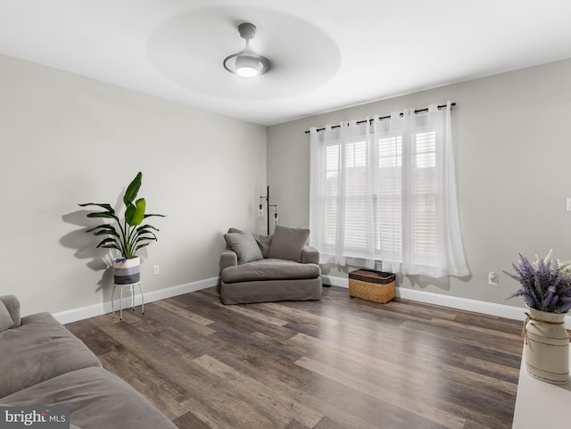 living room with ceiling fan, baseboards, and wood finished floors