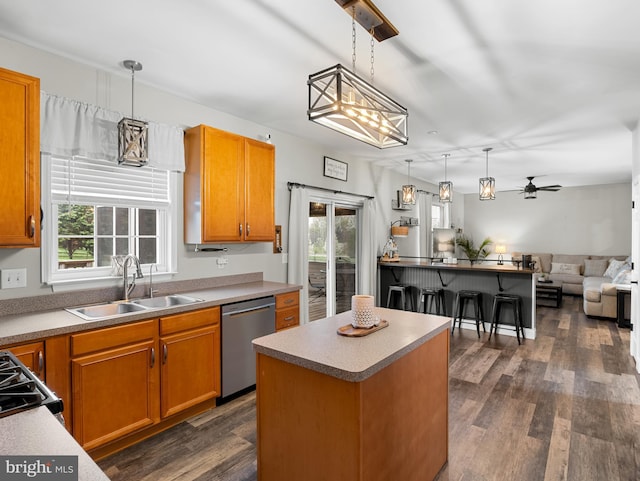 kitchen featuring stainless steel dishwasher, dark wood-style flooring, a sink, and a healthy amount of sunlight