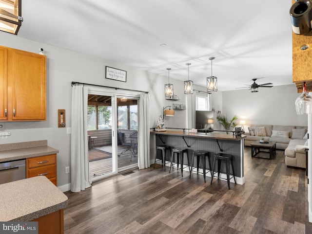 kitchen featuring open floor plan, dark wood finished floors, a ceiling fan, and a kitchen breakfast bar