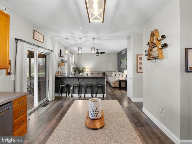 dining area featuring dark wood finished floors, baseboards, and ceiling fan