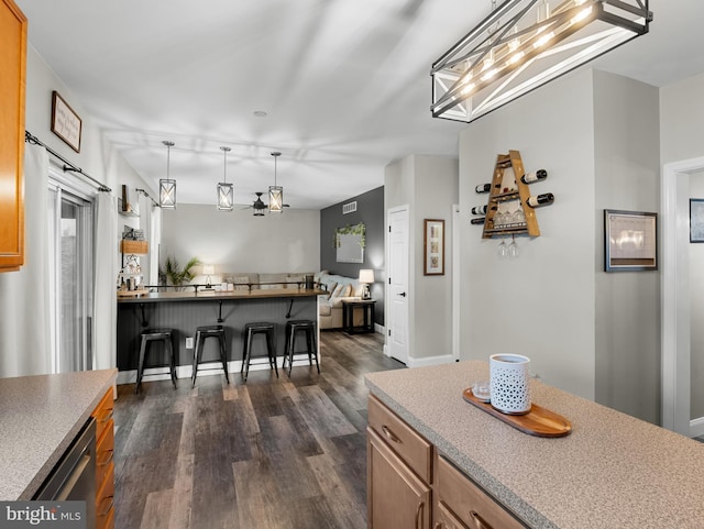 kitchen featuring a kitchen breakfast bar, open floor plan, dark wood-type flooring, dishwasher, and hanging light fixtures