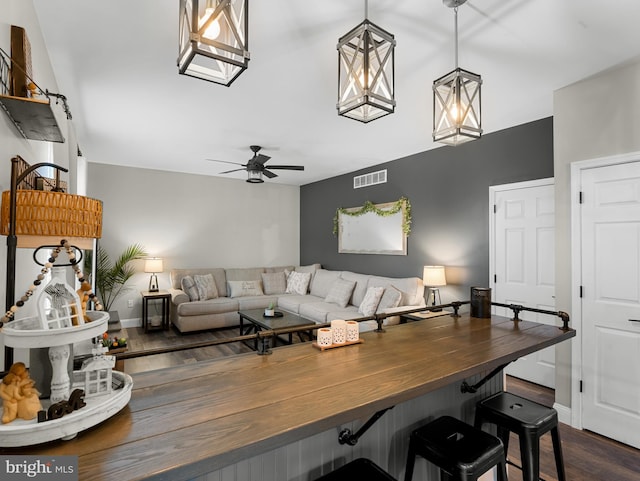 living room featuring dark wood-style flooring, visible vents, ceiling fan, and baseboards