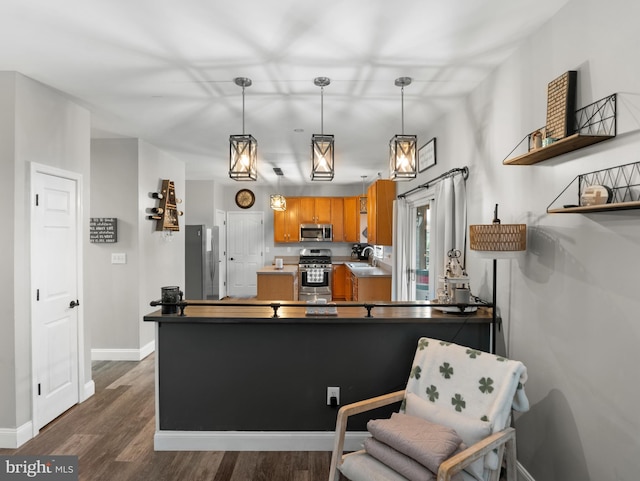 kitchen featuring baseboards, dark wood-type flooring, brown cabinetry, stainless steel appliances, and a sink