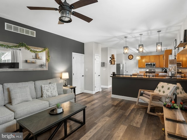 living area with visible vents, baseboards, a ceiling fan, and dark wood finished floors