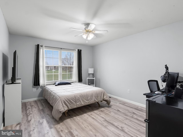 bedroom with baseboards, a ceiling fan, and light wood-style floors