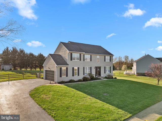 colonial-style house with a front lawn, fence, a garage, and driveway